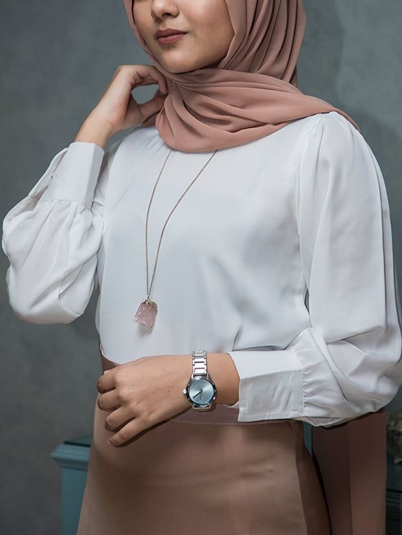 Girl wearing a white satin top with cuffed sleeves and a hijab