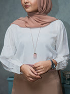 Girl wearing a white satin top with cuffed sleeves and a hijab